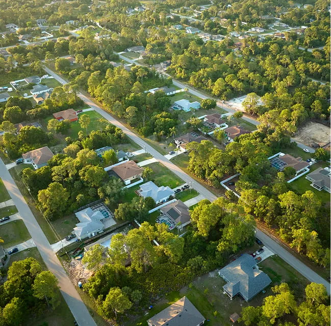 Aerial view of a suburban residential neighborhood surrounded by trees and houses