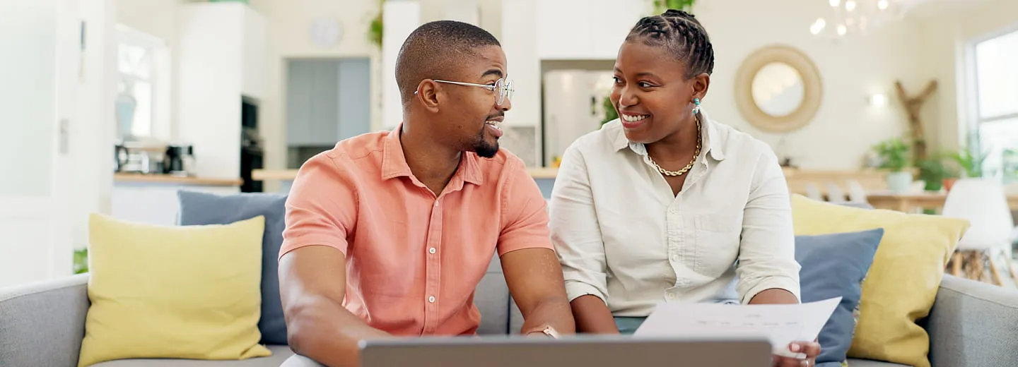 A couple sitting at home reviewing documents together and smiling