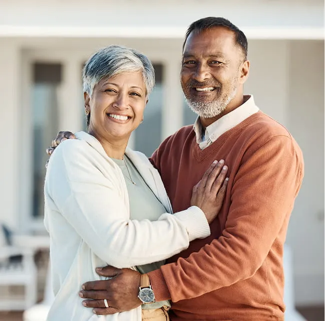 Smiling older couple standing together outdoors, representing a happy and secure retirement
