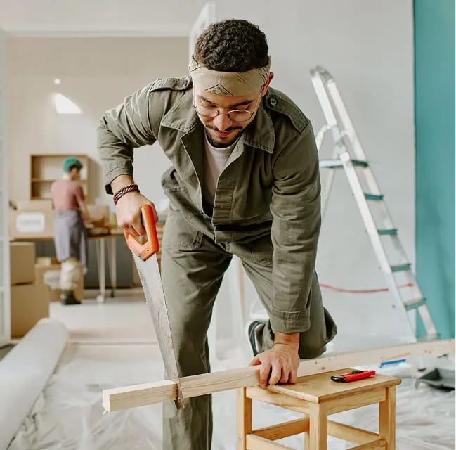 Person cutting wood during a home renovation project inside a house