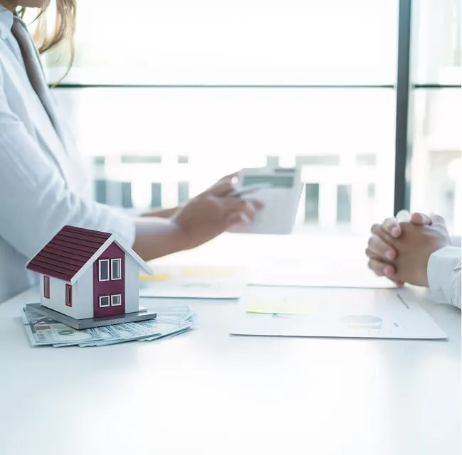 Mortgage consultation with a model house, documents, and a credit card during a home loan discussion