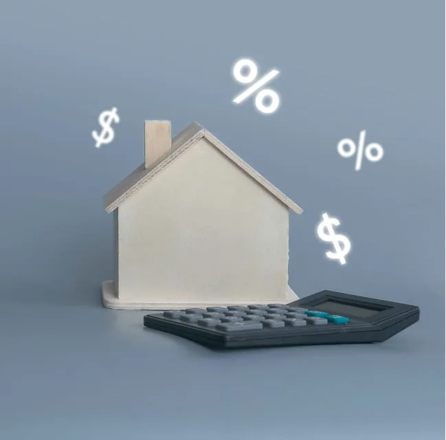 Model house next to a calculator with percentage and dollar symbols representing mortgage interest rates