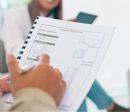 Close-up of hands reviewing an income statement financial report during a consultation