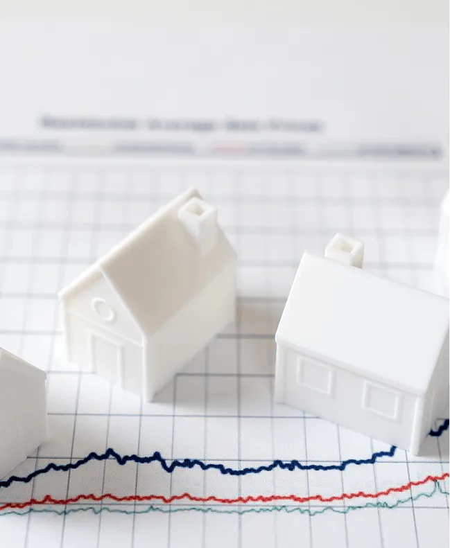 Miniature model houses placed on financial chart representing real estate market trends and home values
